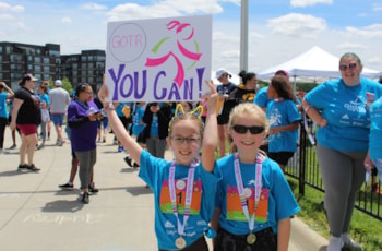 Two GOTR Particpants at a 5K Finish Line with a "You Can!" sign